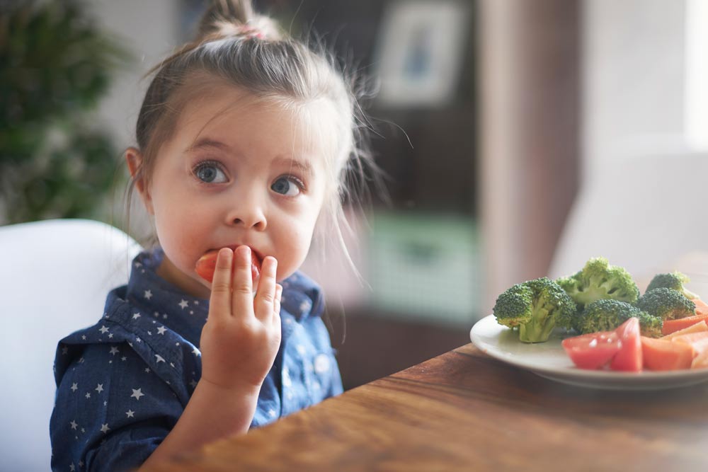 A young child is eating tomatoes
