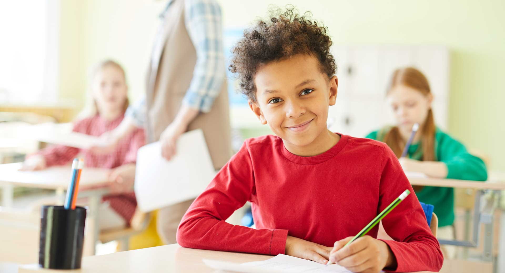 A child sitting at his desk in his classroom, doing some work