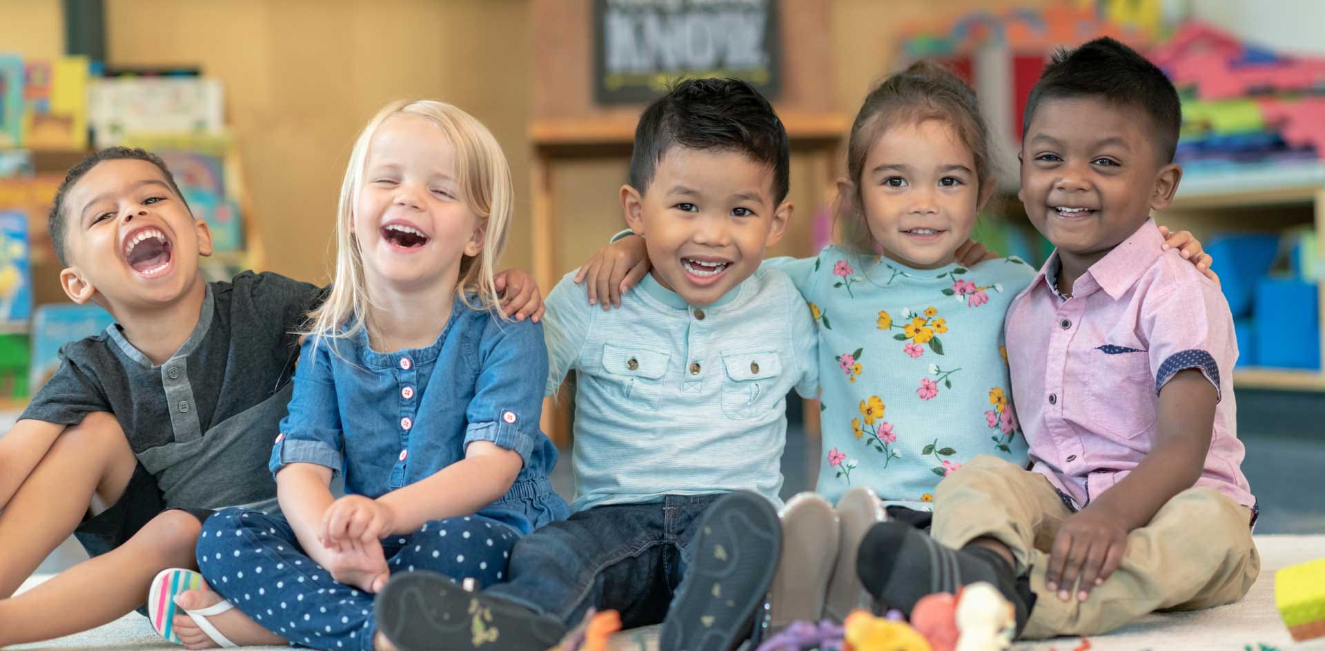 A group of young children holding each other, smiling and laughing